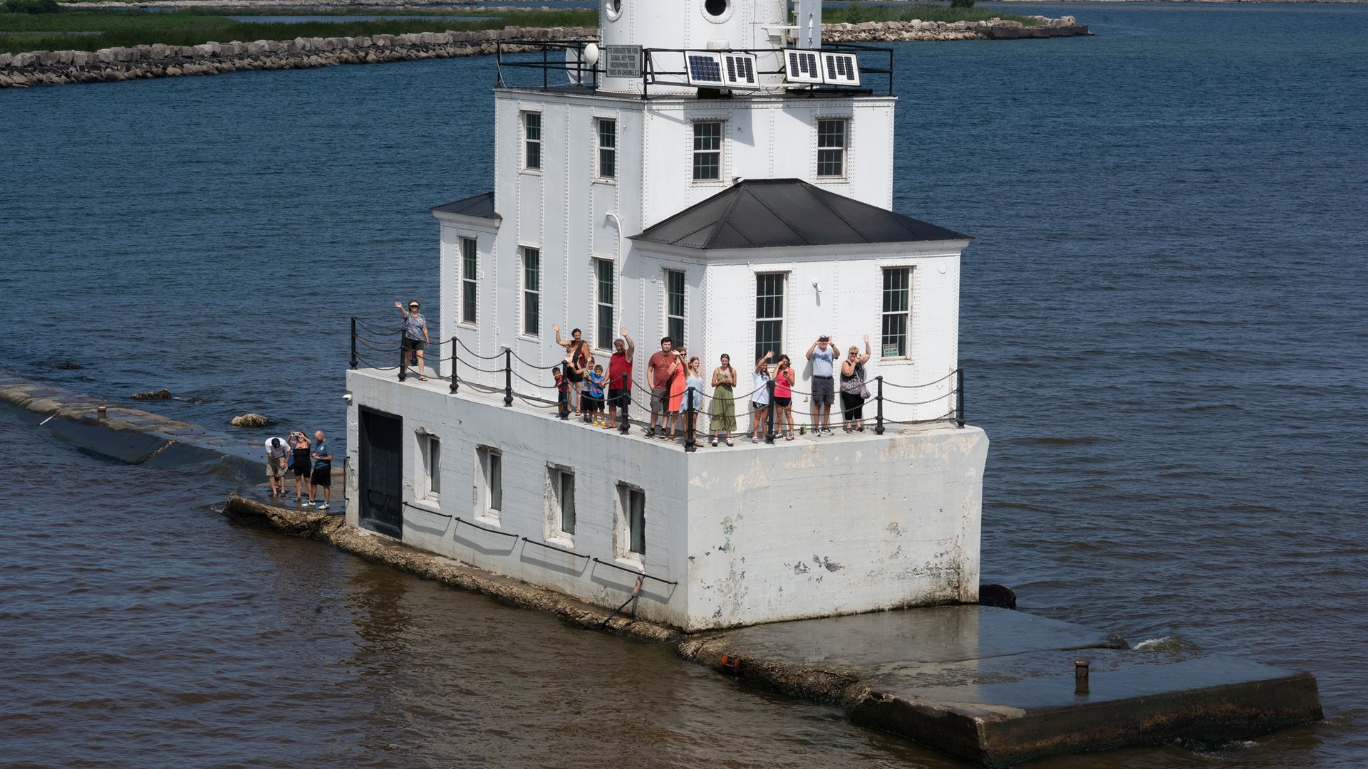 people waving on lighthouse