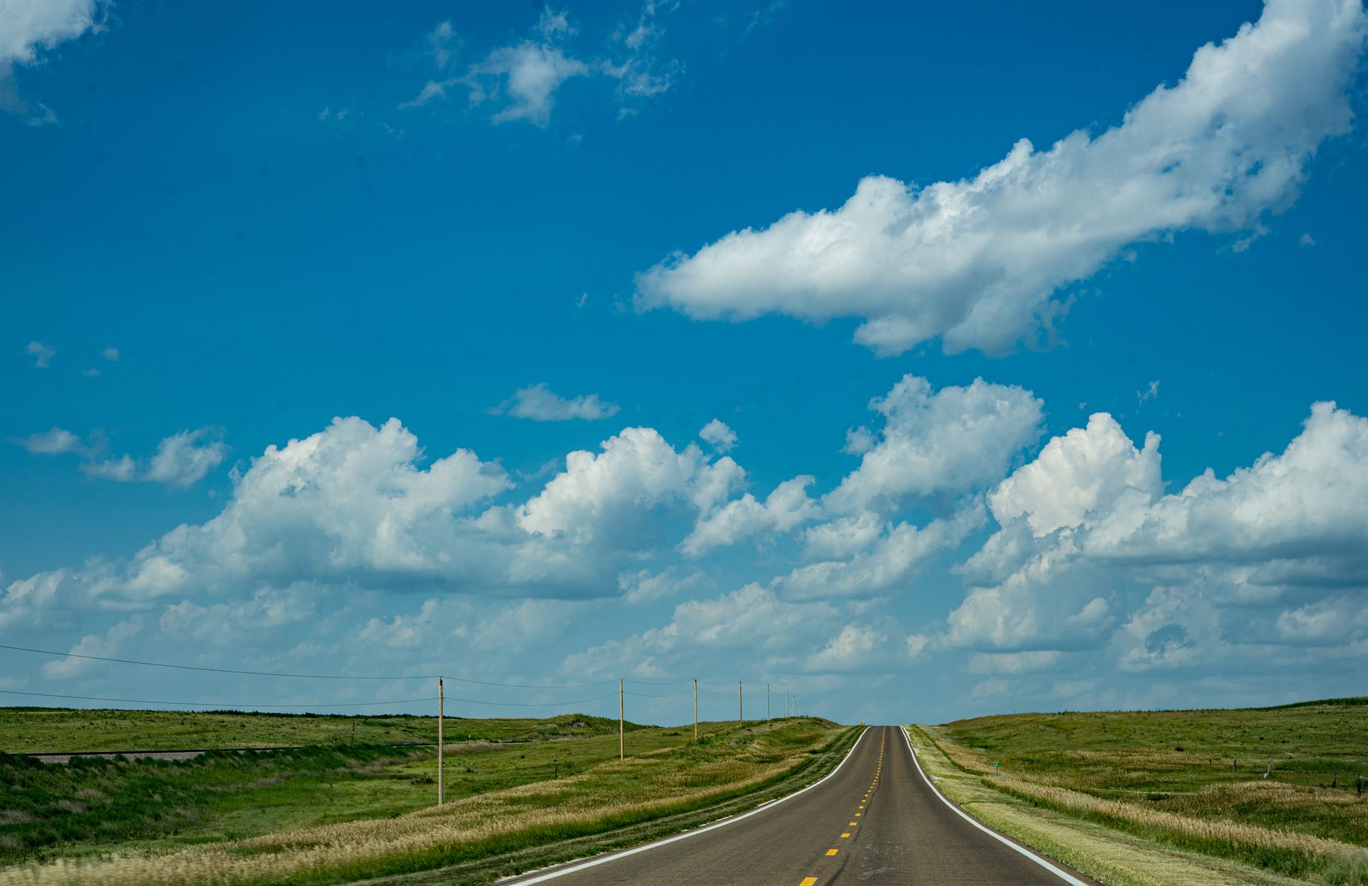 long road with green grass and blue sky